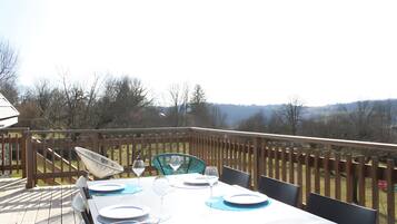 Un espace de restauration en plein air avec une table dressée pour quatre personnes, des chaises et une vue sur le paysage environnant.