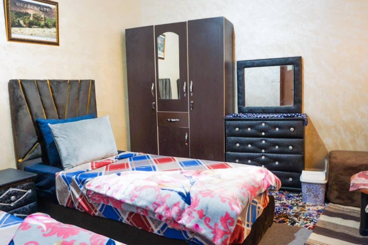 Um quarto com cama, guarda-roupa, penteadeira e espelho.
