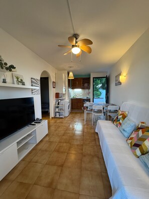 Una sala de estar con televisión, sofá y comedor.