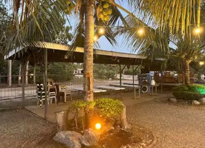 An outdoor seating area with tables and chairs, a covered pavilion, and a palm tree. - Ashelma Resort (Dauis)
