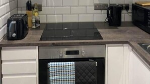 Una cocina moderna con armarios blancos, una hornilla negra y una campana extractora de acero inoxidable.