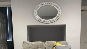 Una sala de estar moderna con un sofá gris, una mesa de centro y un espejo decorativo en la pared.