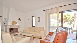 Una sala de estar con chimenea, sofá y sillón de cuero.