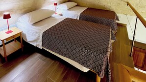 Een slaapkamer met twee bedden, een nachtkastje, een lamp en een houten vloer.