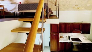 Een kleine keuken met houten kastjes, een eettafel en een zithoek.