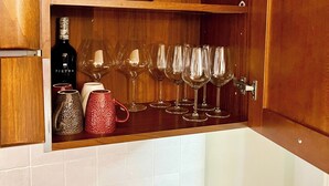 Een houten kastje met wijnglazen en een waterkoker.