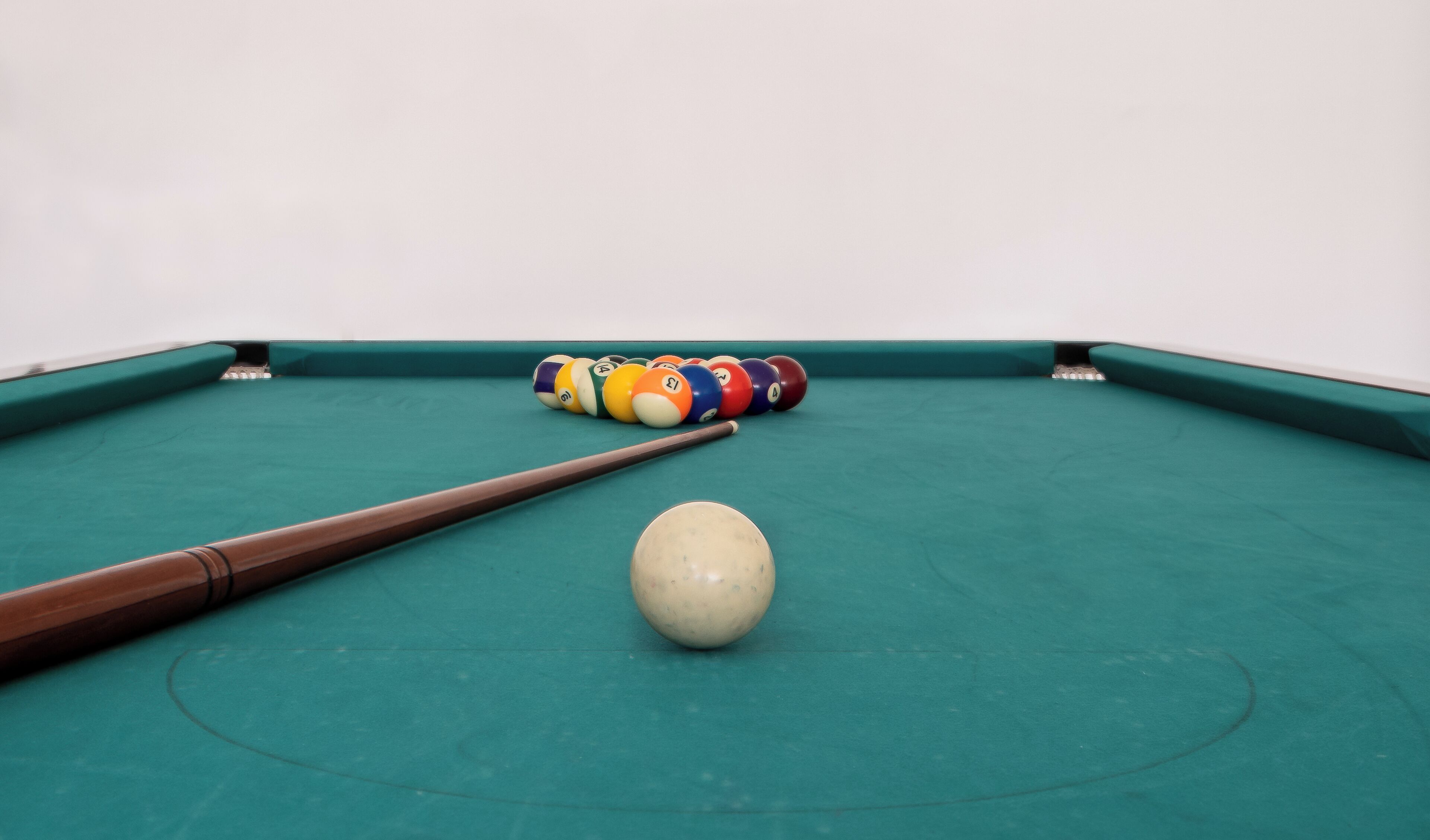 A pool table with a cue stick and billiard balls.