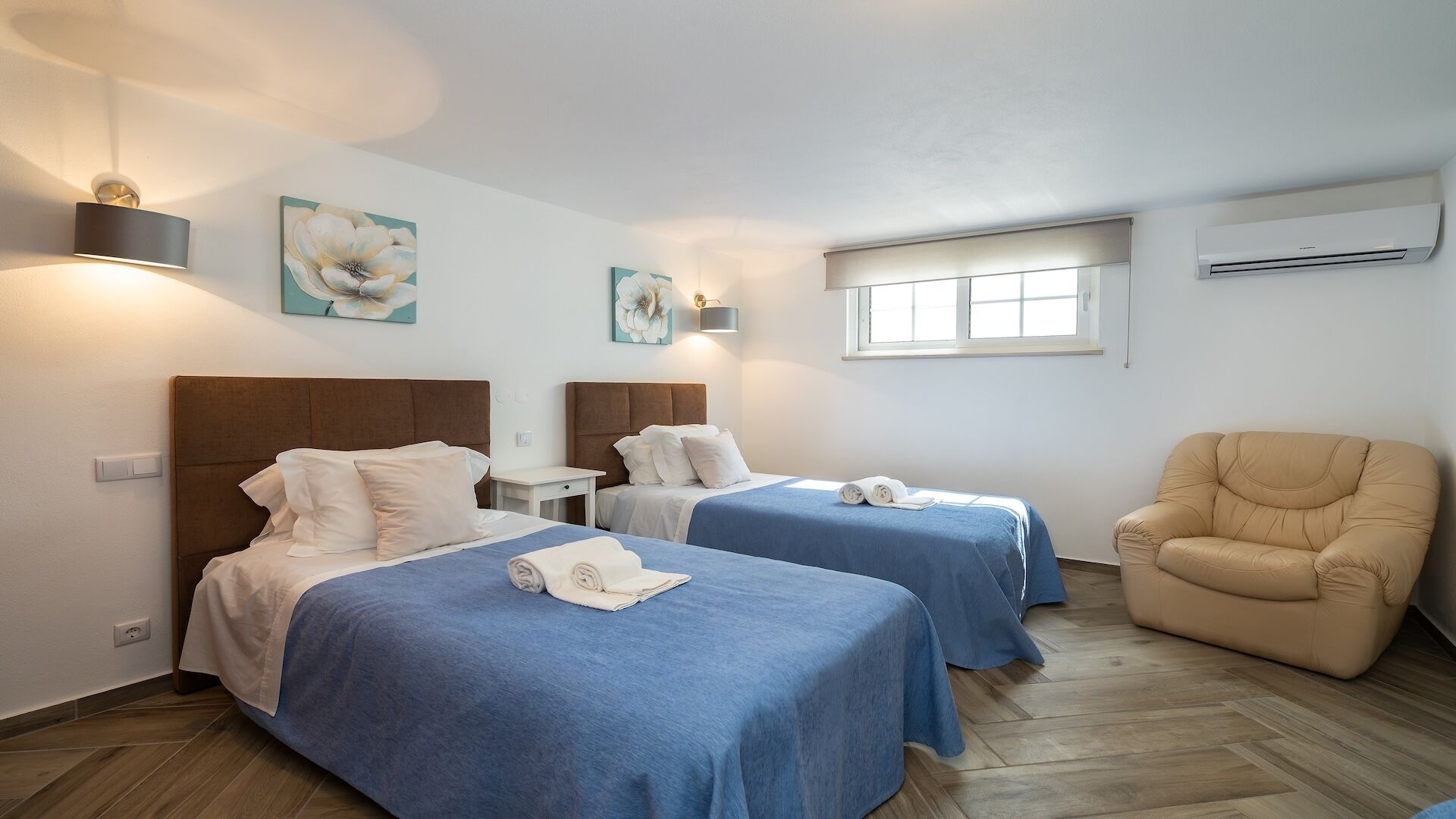 Hotellihuone, jossa on kaksi sänkyä, tuoli ja ikkuna.