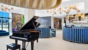 Ein Flügel in einer geräumigen Lobby mit einer modernen Bar und einem großen Fenster mit Blick nach draußen.