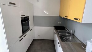 Een moderne keuken met witte kasten, een ingebouwde oven, een spoelbak en een aanrecht.
