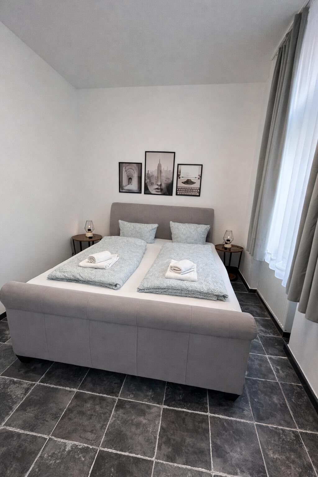 Ein modernes Schlafzimmer mit einem großen Bett, zwei Nachttischen und drei gerahmten Bildern an der Wand.