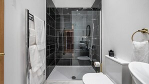 Ein modernes Badezimmer mit einer Glaskabine zur Dusche, einer weißen Toilette und einem Waschbecken.