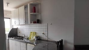 Een keuken met witte kasten, een granieten aanrechtblad en een gasfornuis.