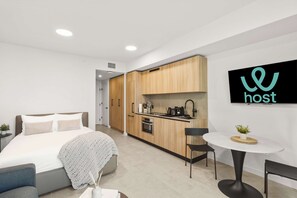 A modern hotel room with a bed, bedside table, and a small kitchenette. - Downtown Studio | City Views | Free Parking (Miami)