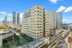 A high-rise building with multiple floors, a prominent central entrance, and a surrounding urban environment with other buildings and a highway. - Downtown Studio | City Views | Free Parking (Miami)