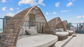 Eine Dachterrasse mit Korbsessel-Lounge und Blick auf die Stadt.