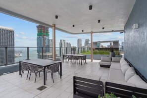 A balcony with a dining table and chairs, a sofa, and a view of the city skyline and water. - Downtown Studio | City Views | Free Parking (Miami)