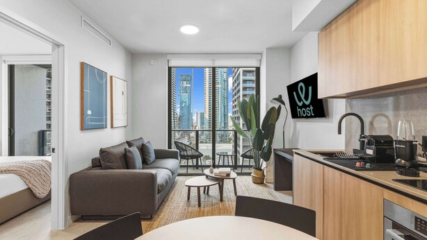 A modern apartment with a living area, kitchen, and large windows offering city views. - Stylish 1BR+Den | Pool / CoWork | Free Parking (Miami)