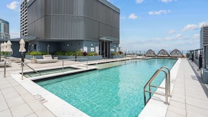 Un edificio moderno con piscina, area relax all'aperto e cielo sereno.