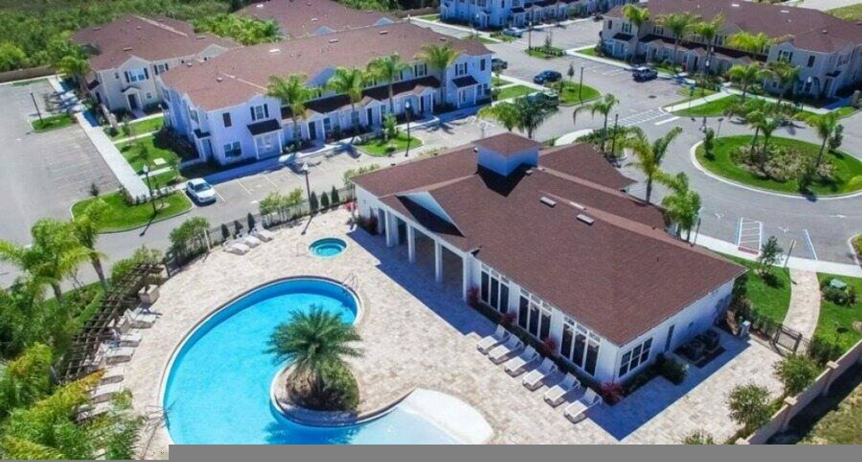 A residential area with a swimming pool, multiple houses, and a well-maintained lawn.