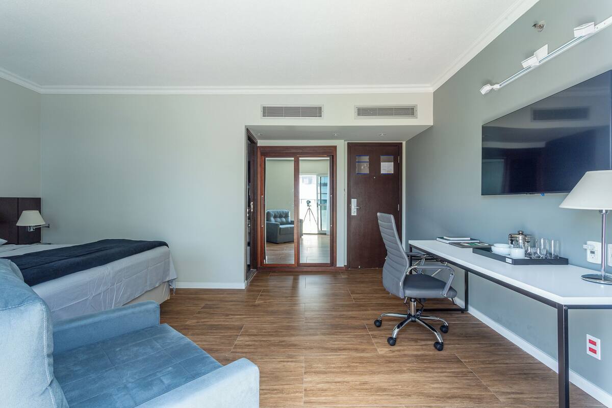 Een hotelkamer met een bed, een bureau, een stoel en een bank.