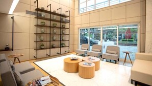 A modern lobby with a high ceiling, a large window with a view of the street, and a seating area with three round wooden tables and four chairs. - Hotel Blue Tree Premium by Wecare (São Paulo)