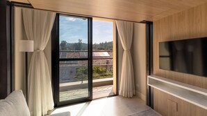 A modern room with a large TV, sliding glass doors to a balcony, and a sofa. - 1986 Apparts  (Águas de São Pedro)