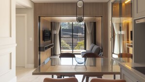 A modern dining area with a glass table, chairs, a television, and a view of the outdoors. - 1986 Apparts  (Águas de São Pedro)