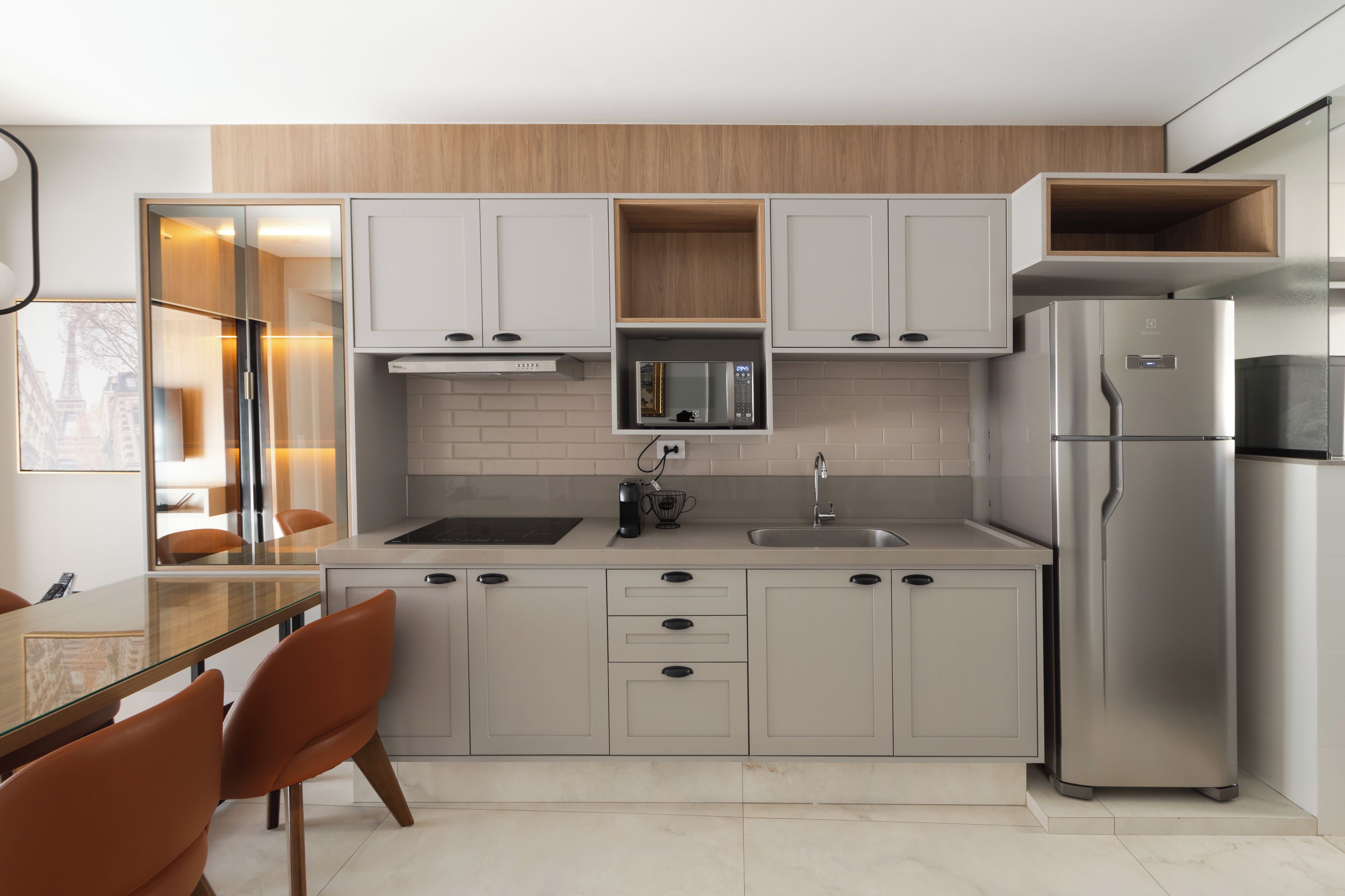 Una cocina moderna con microondas integrado, refrigerador de acero inoxidable y encimera de madera.