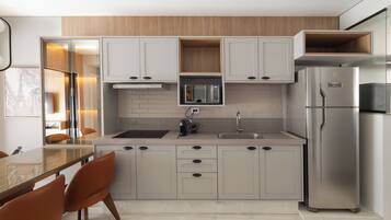 Una cocina moderna con microondas integrado, refrigerador de acero inoxidable y encimera de madera.