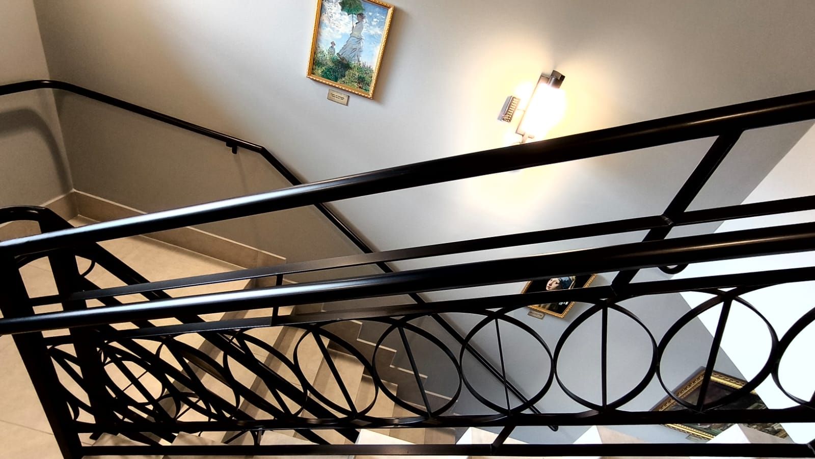 A staircase with a black metal railing and a wall-mounted light fixture.