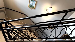 Una scala con ringhiera in metallo nero e un punto luce a parete.