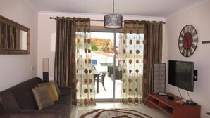 Una sala de estar con sofá, televisor, mesa de centro y alfombra estampada.