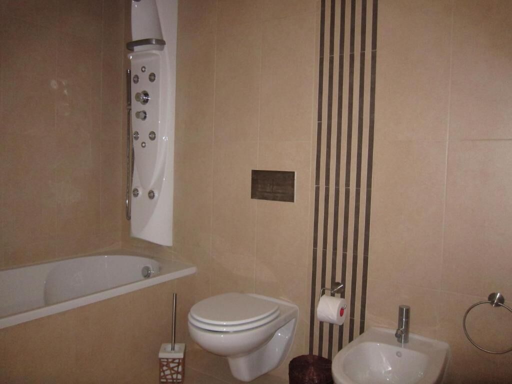 Een badkamer met een badkuip, toilet, bidet en een handdoekhouder.