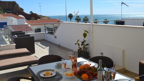 Terraza en la azotea con una mesa lista para una comida, con vistas a la costa.