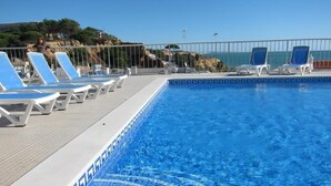 Una piscina con azulejos azules y sillones blancos.