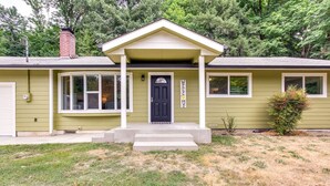 A single-story house with a front porch, a black front door, and a 'WELCOME' sign.