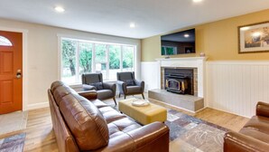 A living room with a fireplace, leather sofas, and a television mounted above it.