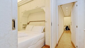 Una camera d'albergo con un letto grande, un armadio e un corridoio che porta a un'altra stanza.