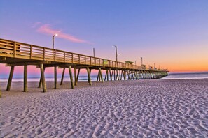 A wooden pier extending over a sandy beach with a clear sky. - Cooleemee Place South, Oceanside Duplex in Emerald Isle, NC! (Emerald Isle)