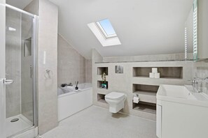 A modern bathroom with a skylight, a shower, a bathtub, and a toilet. - Modern Ensuite Home with Drive and easy M6 Access (Wednesbury)