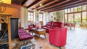 Un salón amplio con un sofá de cuero rojo, una mesa de centro de madera y una chimenea.
