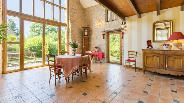 Un comedor con una mesa, sillas, un reloj y vistas al exterior.