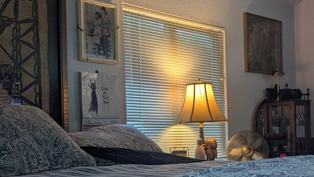 A bedroom with a bed, a lamp, a fan, and framed pictures on the wall. - Westside Charmer, located in Ukiah, CA. (Ukiah)