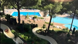 Ein Poolbereich mit Rutsche, umgeben von viel Grün und einem Sandstrand.
