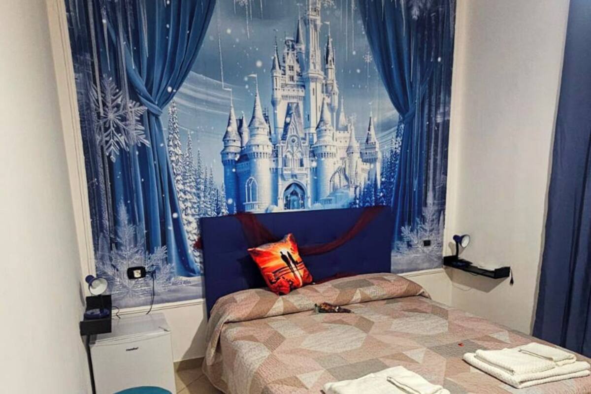 A bedroom with a bed, a nightstand, a dresser, and a wall tapestry.