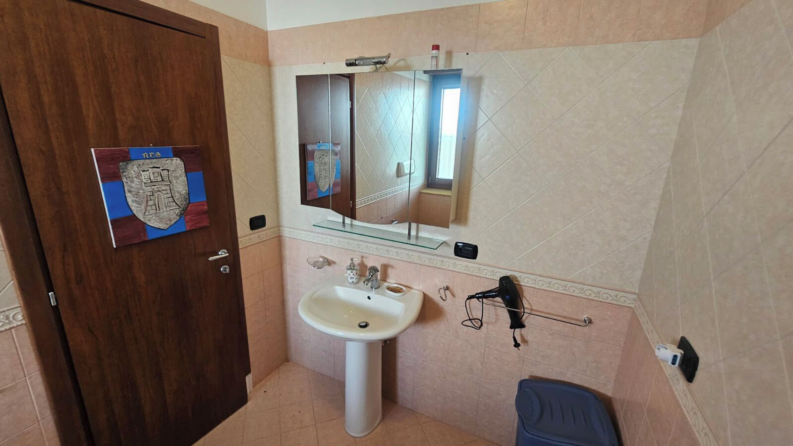Une salle de bain équipée d’un lavabo, d’un miroir et d’un sèche-cheveux.