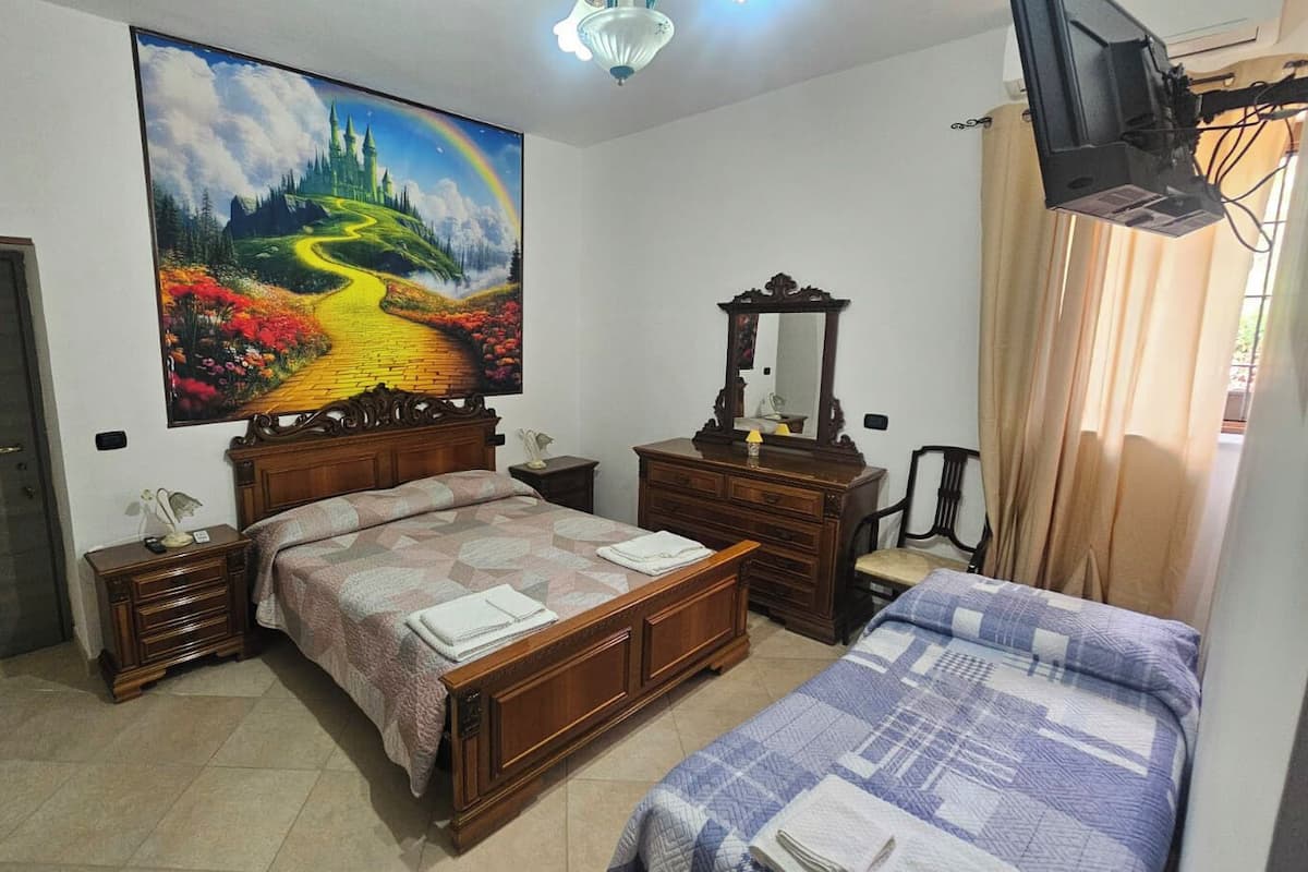 A bedroom with a bed, a dresser, a mirror, a television, and a painting on the wall.