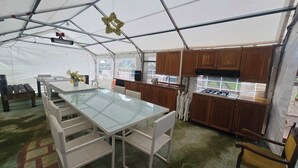 Ett tält med ett glasbord för matplatsen, träskåp och ett köksområde.