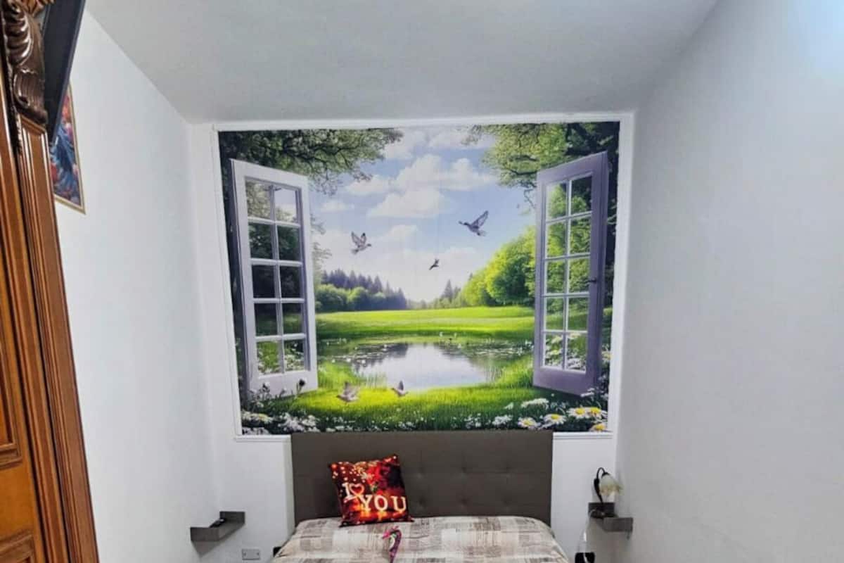 A bedroom with a bed, a pillow, a chair, and a wall mural.